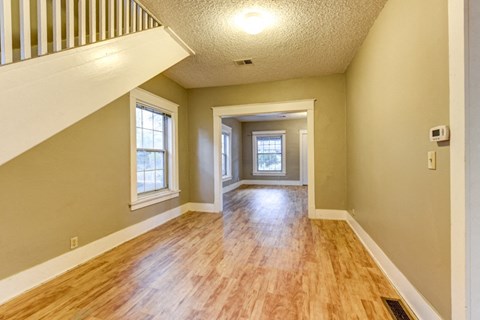 A room with wooden floors and a staircase leading to the upper floor.