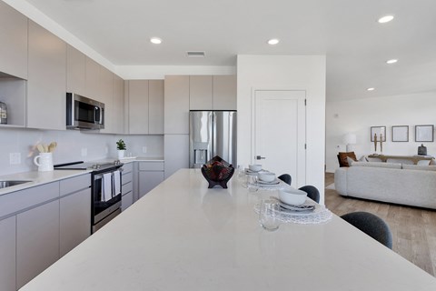 an open kitchen and living room with a white counter top