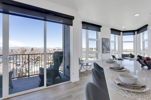 an open living room with a dining table and chairs and a balcony with a view