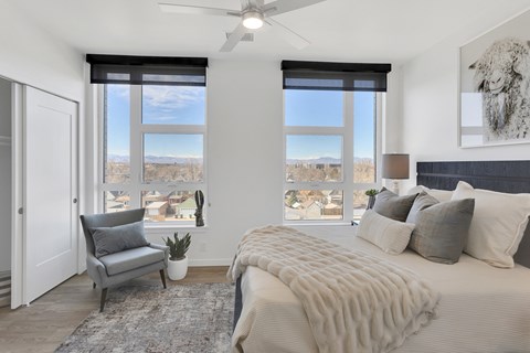 an open bedroom with a bed and a chair and windows