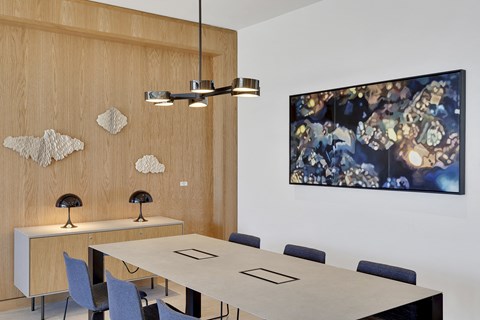 a conference room with a table and chairs and a painting on the wall
