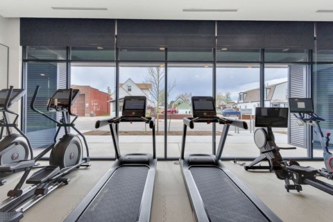 a gym with treadmills and a window view of the street
