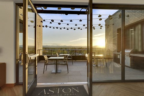 a balcony with a view of the sunset and a patio with tables and chairs