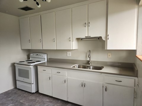 A kitchen with white cabinets and a stove top oven.