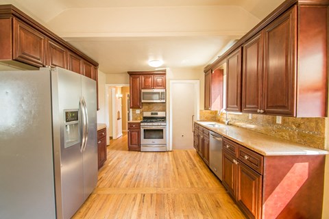 A kitchen with wooden cabinets and a stainless steel refrigerator.