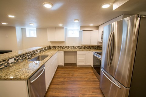 A modern kitchen with a stainless steel refrigerator and granite countertops.