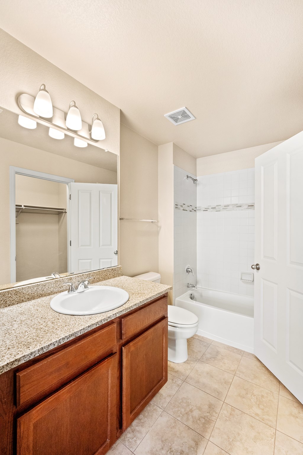 A bathroom with a sink, mirror, toilet and bathtub.
