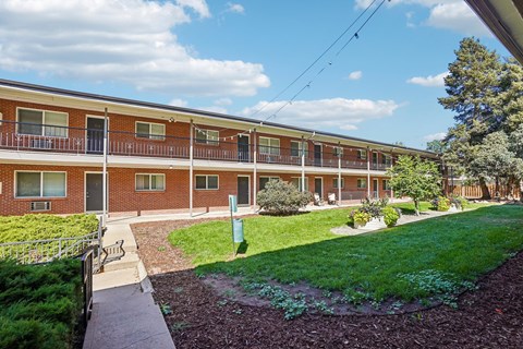 A red brick apartment building with a green lawn in front.