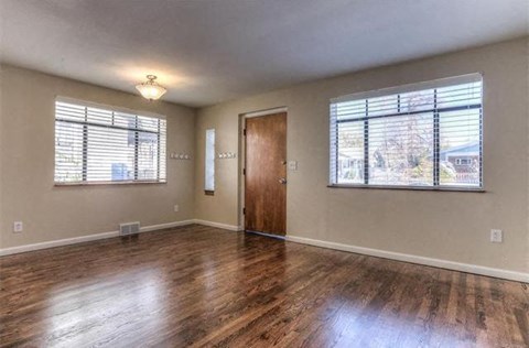 an empty living room with wood floors and a window