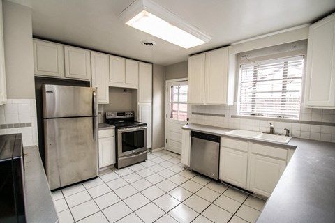 A kitchen with white cabinets and a stainless steel refrigerator.