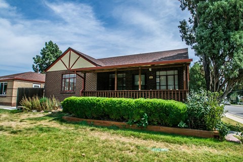 A house with a red roof and a green hedge in front.
