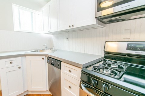 a kitchen with white cabinets and a stove and a sink