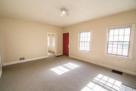 A room with a red door and two windows.