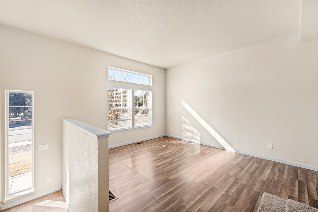 A room with a large window and wooden flooring.
