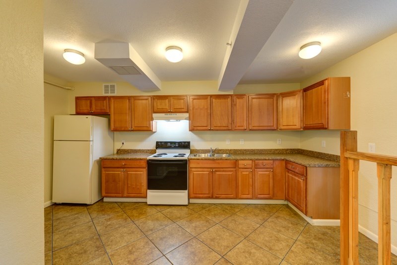 A kitchen with brown cabinets and a white refrigerator.