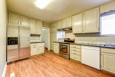A kitchen with white cabinets and wooden floors.