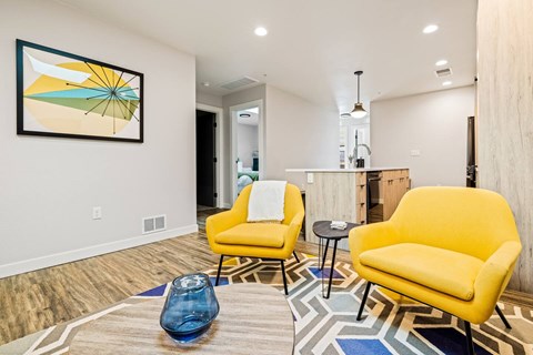 A living room with two yellow chairs and a blue vase on a patterned rug.