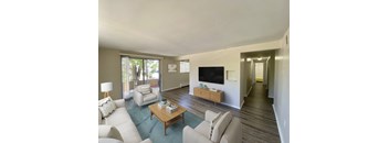 A living room with a white couch, a wooden coffee table, and a flat screen TV.