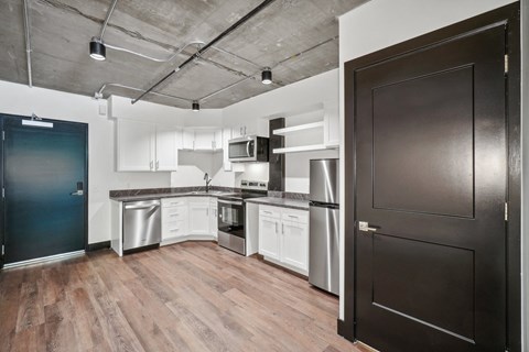 a kitchen with white cabinets and stainless steel appliances and a black door