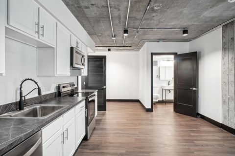 a kitchen with white cabinets and stainless steel appliances and a black door