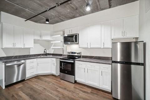 an empty kitchen with stainless steel appliances and white cabinets