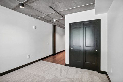 an empty room with a black door and a white rug