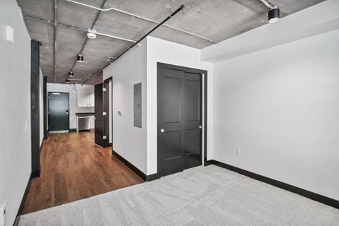 a living room with a gray rug and white walls and a black door