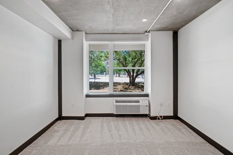 an empty room with a large window and a heater on the floor