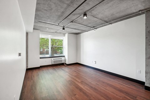 an empty living room with wood floors and a window