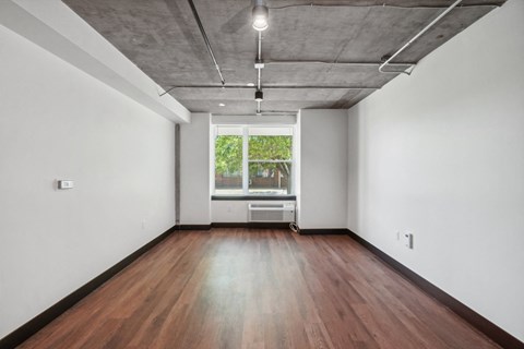 an empty room with wood floors and a window