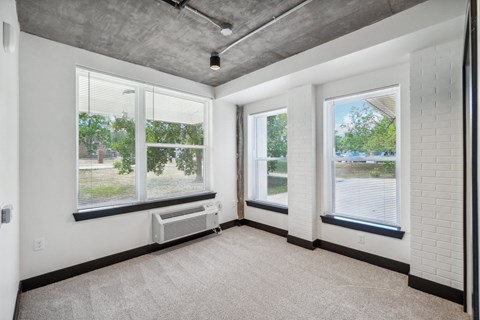 the living room of an empty apartment with three windows