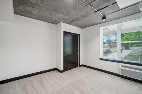 an empty living room with a large window and a door to a hallway
