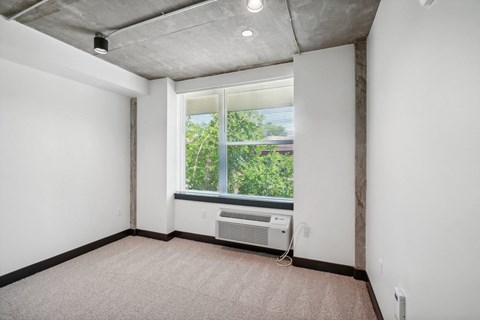 an empty room with a large window and an air conditioner