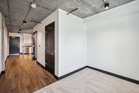 a living room with white walls and wood floors and a black door