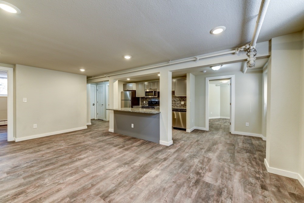 an empty living room with a kitchen in the background