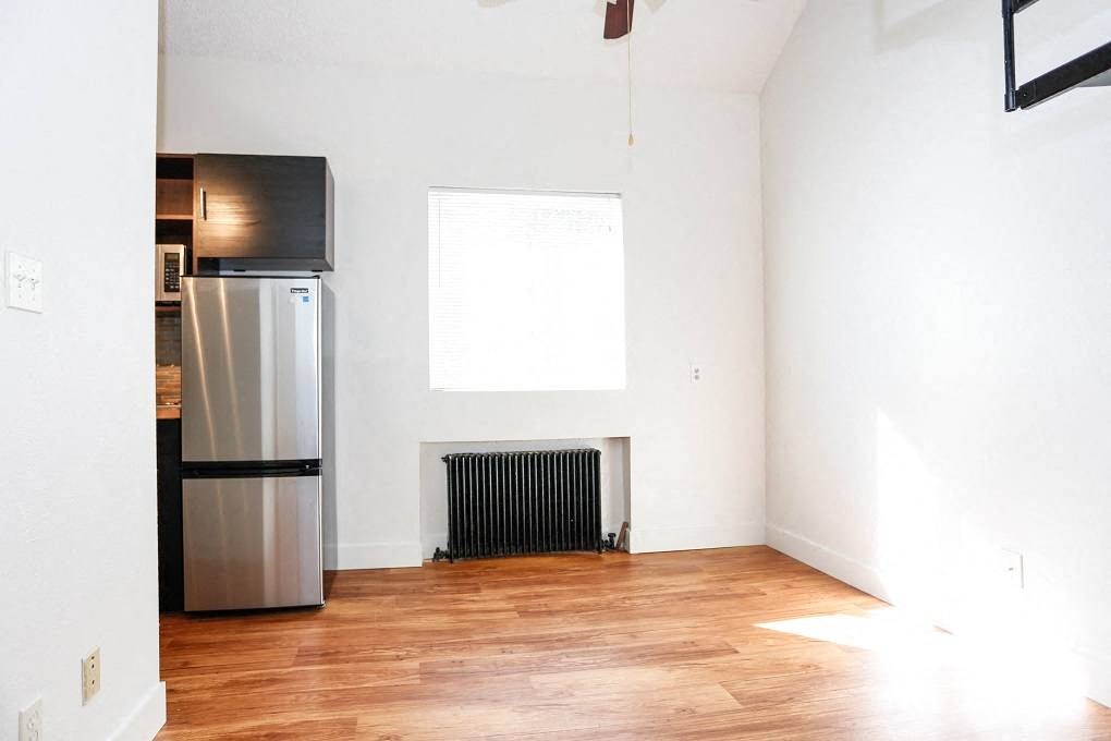 an empty room with a refrigerator and a window