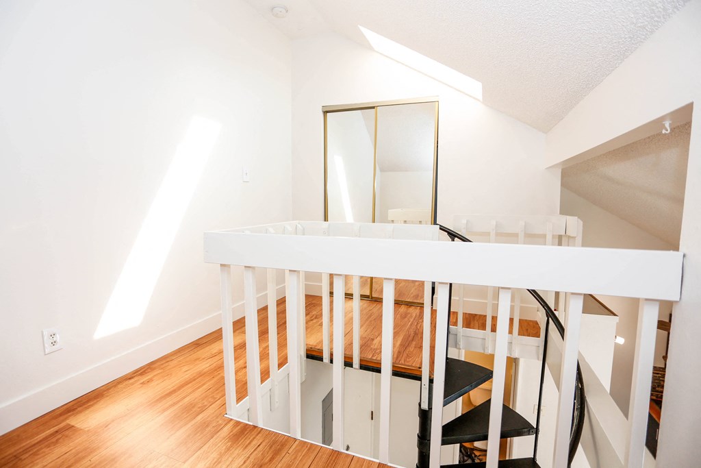 a loft with a white railing and a mirror on top of it