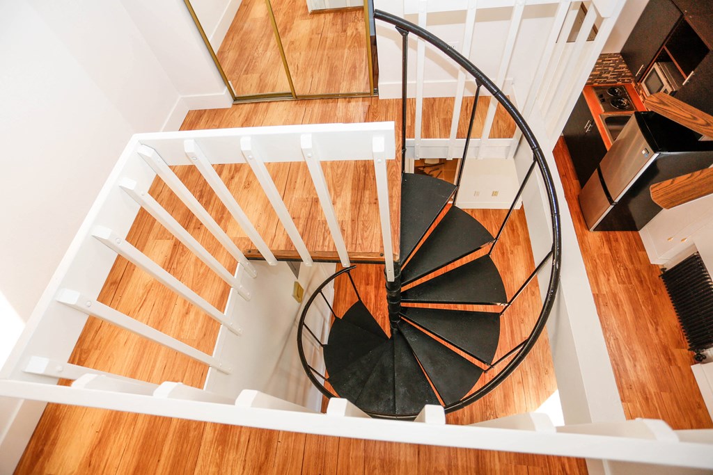 a spiral staircase in a home with wooden floors and a black spiral staircase