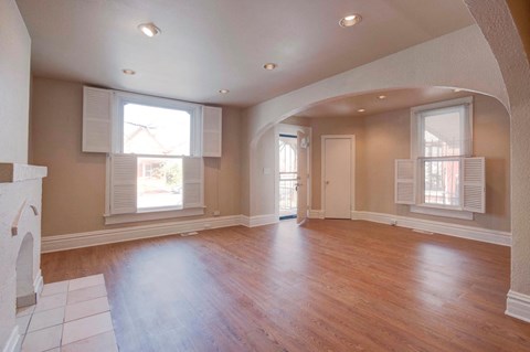 an empty living room with a fireplace and wooden floors