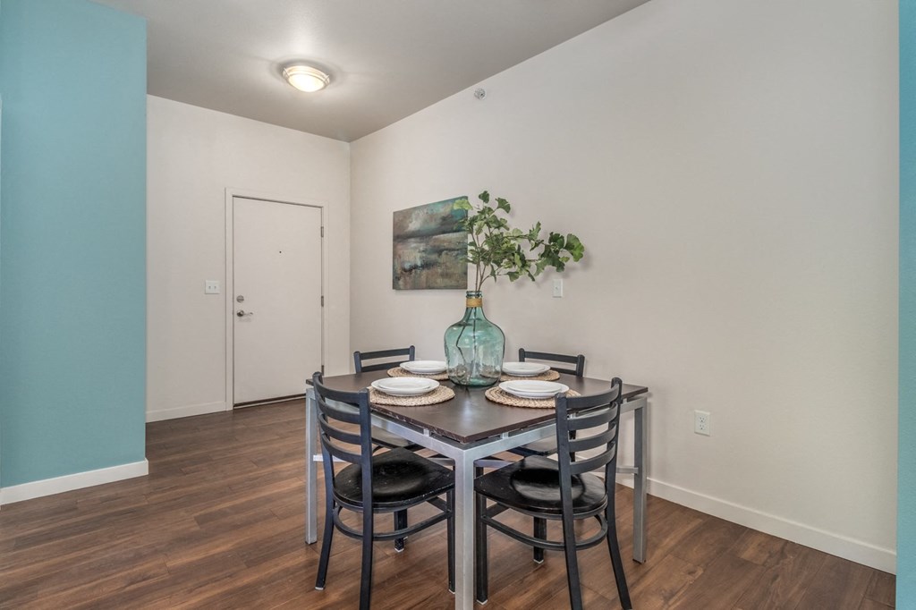 a dining room with a table and chairs and a vase of flowers