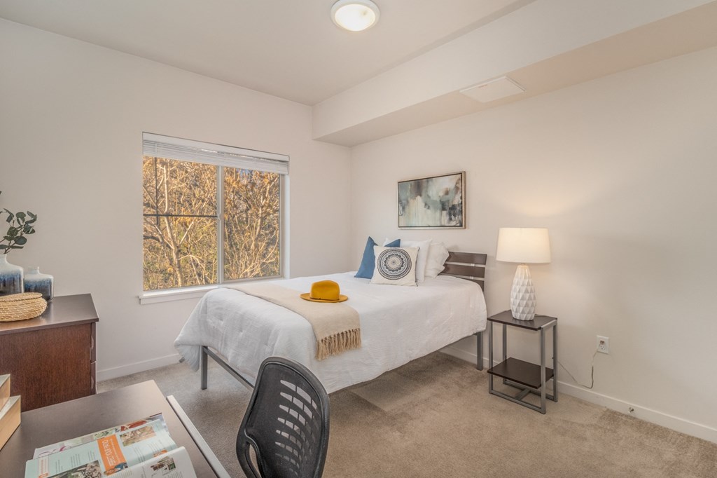 a bedroom with a bed and a desk and a window