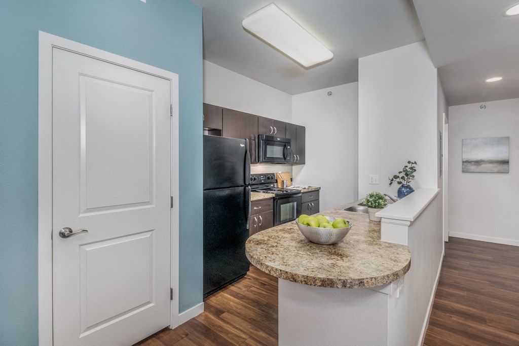 a kitchen with a round granite counter top and a black refrigerator