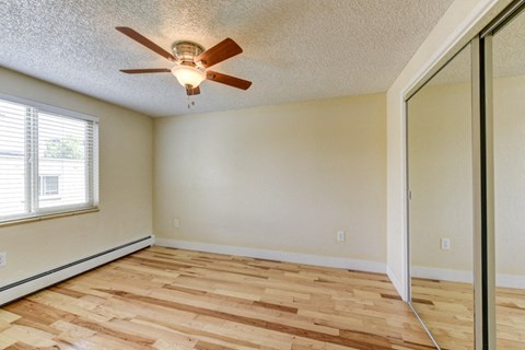 the spacious living room with hardwood floors and a ceiling fan