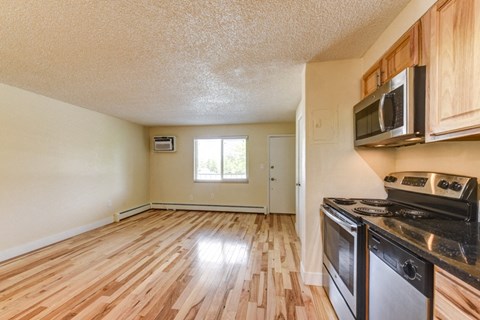 the kitchen of an empty apartment with wood flooring and appliances