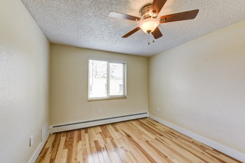 the spacious living room with hardwood floors and a ceiling fan