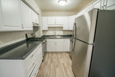 a kitchen with white cabinets and a stainless steel refrigerator