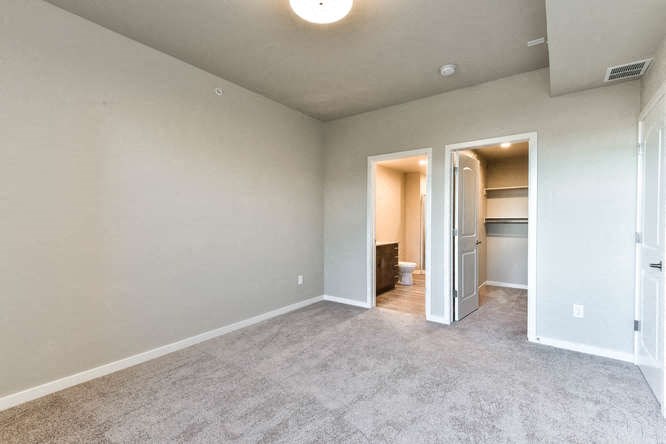 an empty living room with a door to a bathroom