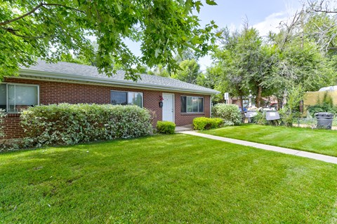 A house with a green lawn and a white pathway leading to the front door.