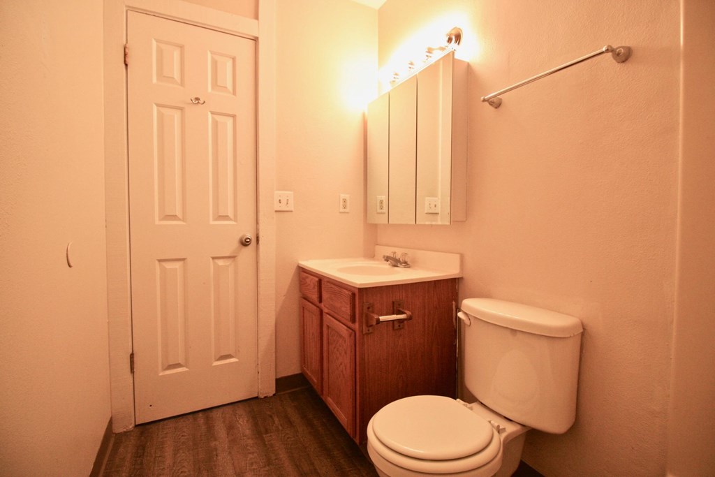 A white toilet sits next to a wooden cabinet in a bathroom.
