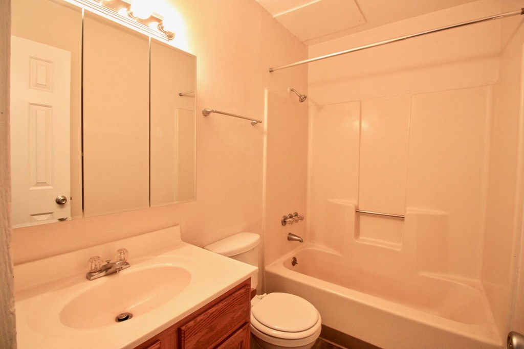A white bathroom with a toilet, sink, and bathtub.